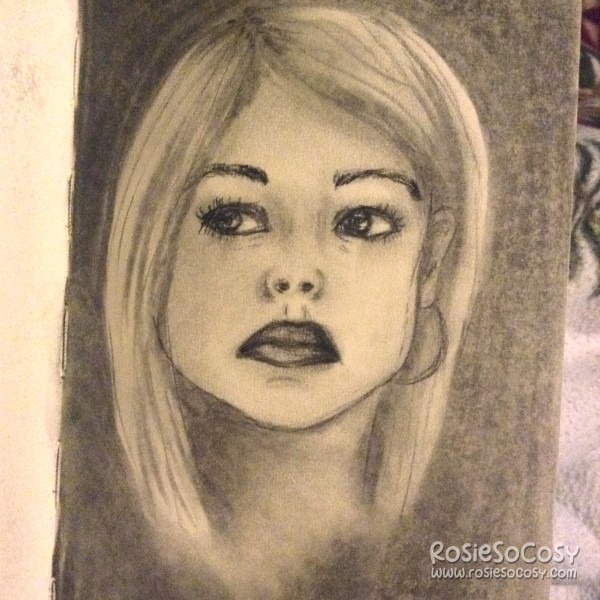 Charcoal drawing of Rose Tyler (portrayed by Billie Piper), the blonde companion to the 9th and 10th Doctor in Doctor Who. Rose is looking to the left. She has a serious look on her face. The corners of her mouth are pointing downwards. She has a hoop earring in her left ear. Her right ear isn't visible since the blonde, straight hair is in front of it. The background is black.