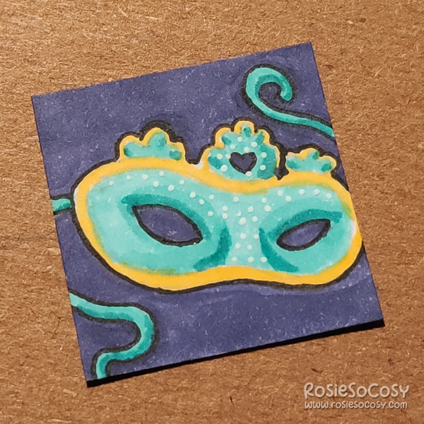An inch sized drawing of a turquoise mask with golden yellow details.