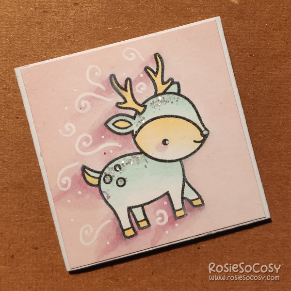 An inch sized card with a light pink background, and a light blue deer which seems to be rushing or running towards (or from) something.