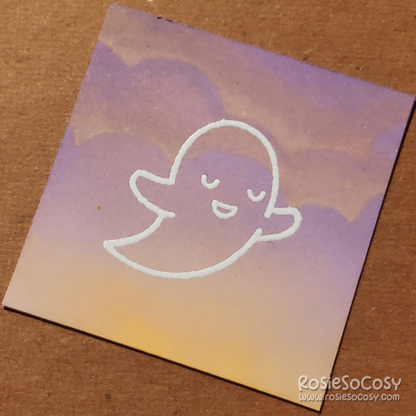 A tiny 2 inch card with a translucent (white outlined) ghost, who is seemingly peaceful, on a soft purple and yellow cloudy background.